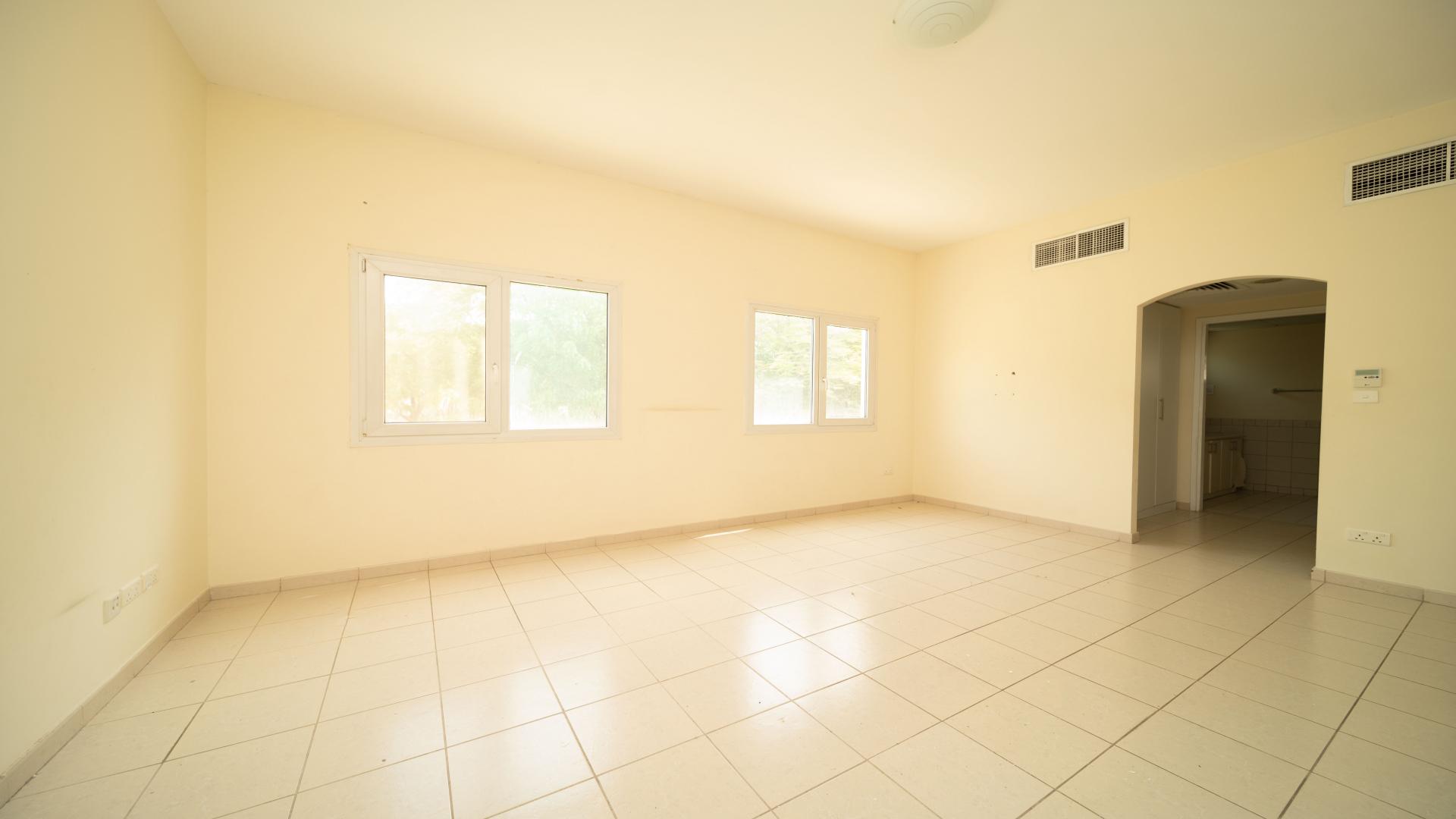 Empty room in three-bedroom villa, Meadows 6, with tiled floors and large windows