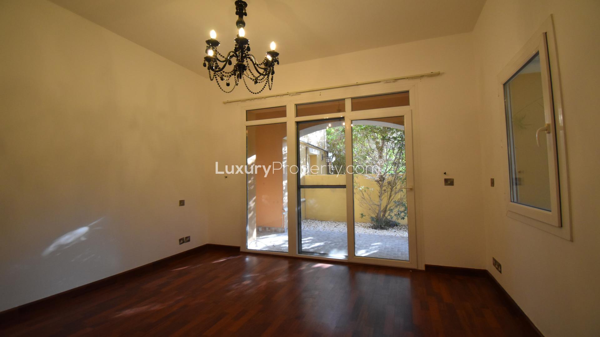 Empty room with wooden flooring, chandelier, and large window in Palmera villa, Arabian Ranches