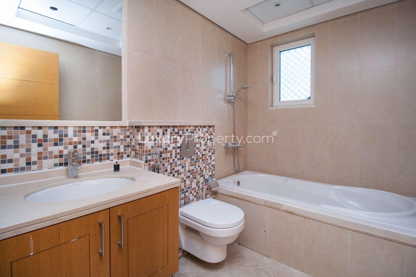 Modern kitchen in Jumeirah Park villa for rent, featuring wooden cabinets and large windows