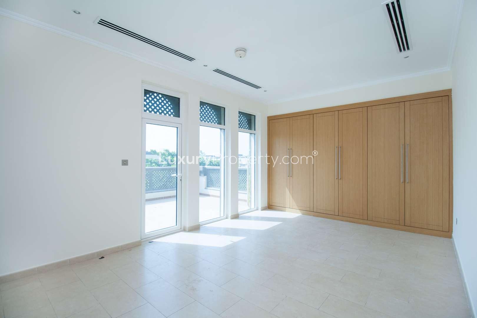 Spacious Jumeirah Park villa exterior with large tree, two garages, and lush greenery