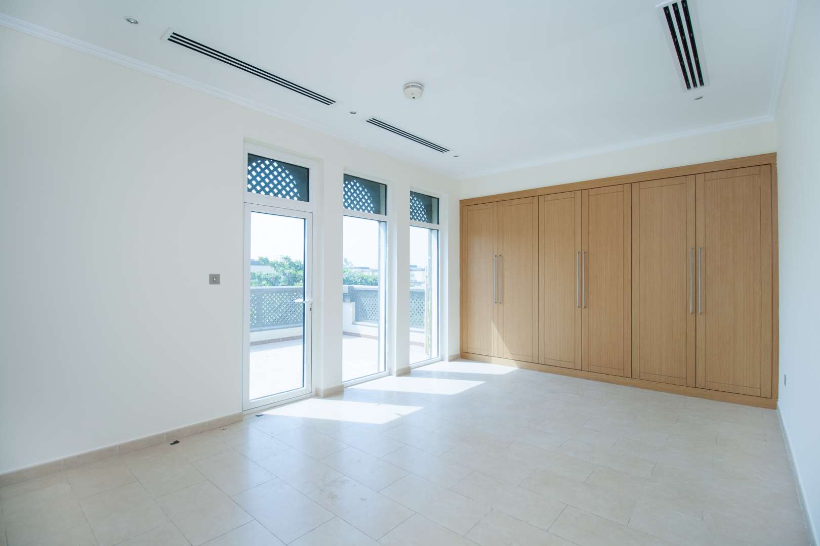 Spacious Jumeirah Park villa exterior with large tree, two garages, and lush greenery