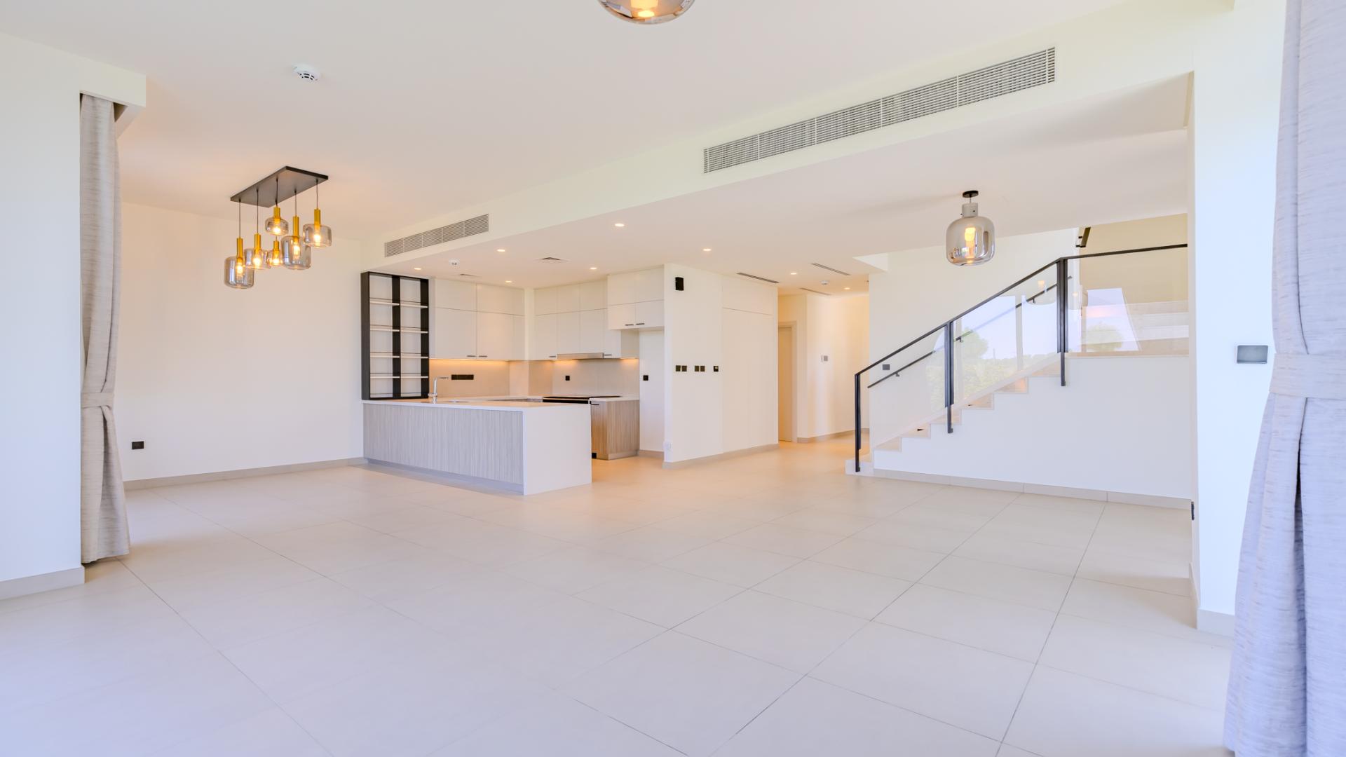 Bright living area in Golf Grove villa, Dubai Hills Estate, with modern kitchen and large windows