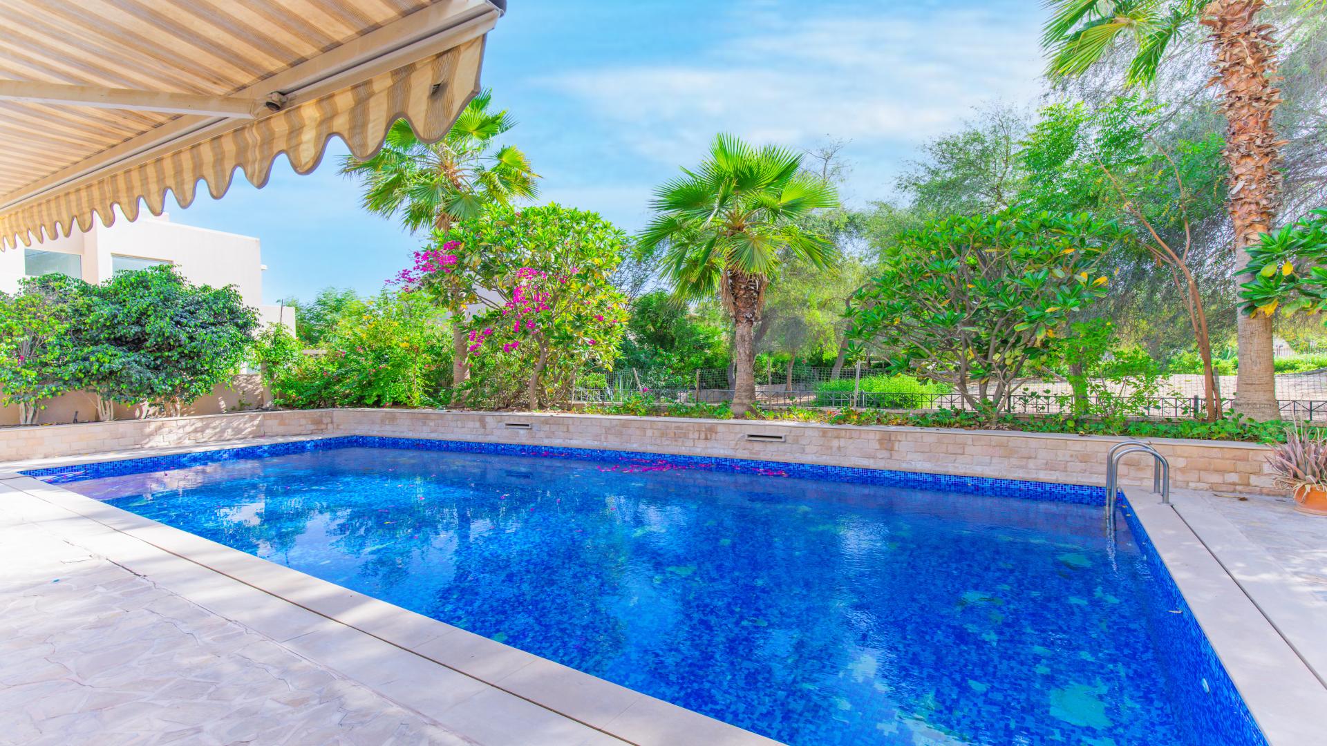 Living room view of Arabian Ranches villa with pool access through large windows