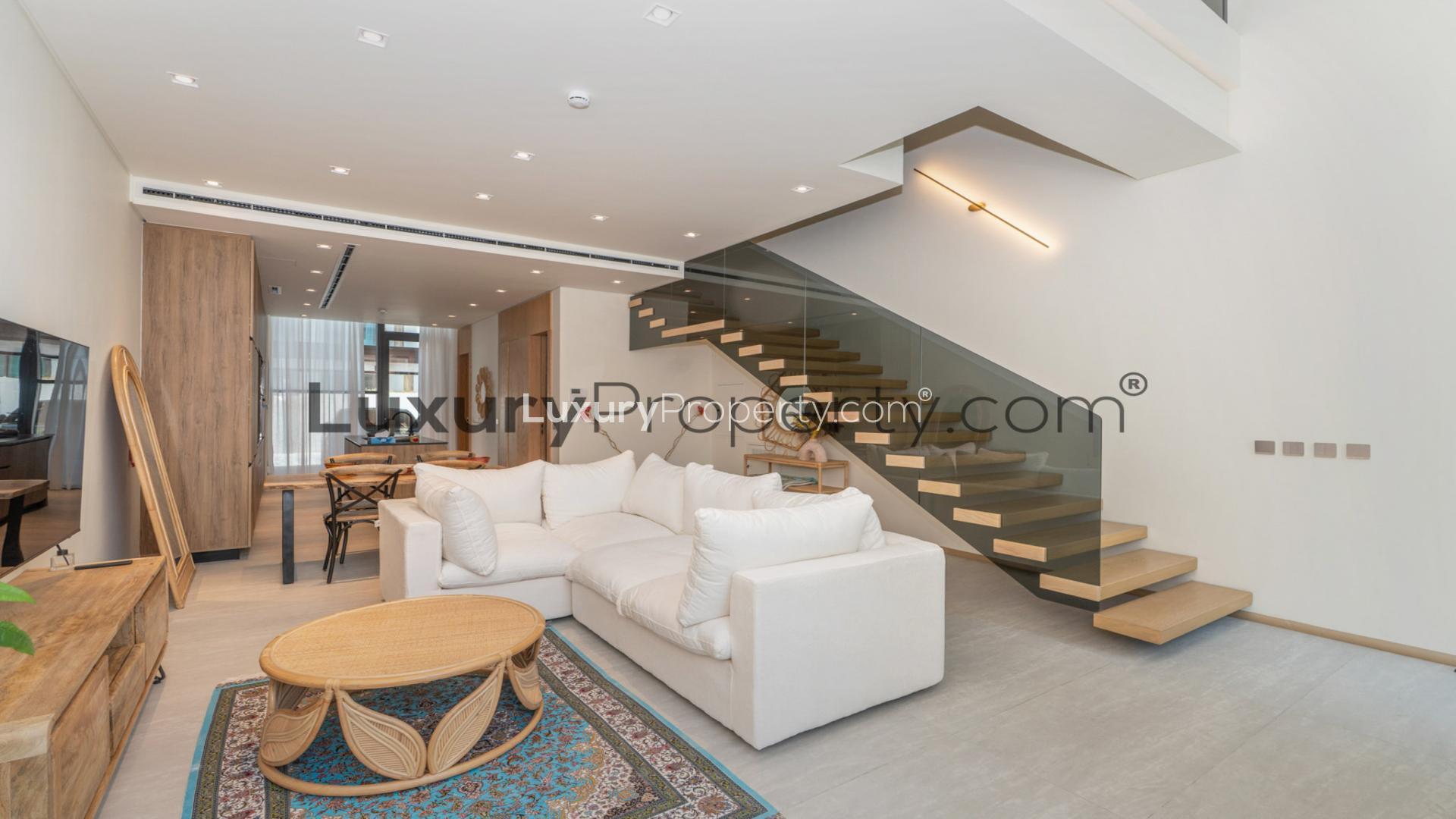 Elegant living room with modern staircase in Jumeirah Village Circle villa for rent.