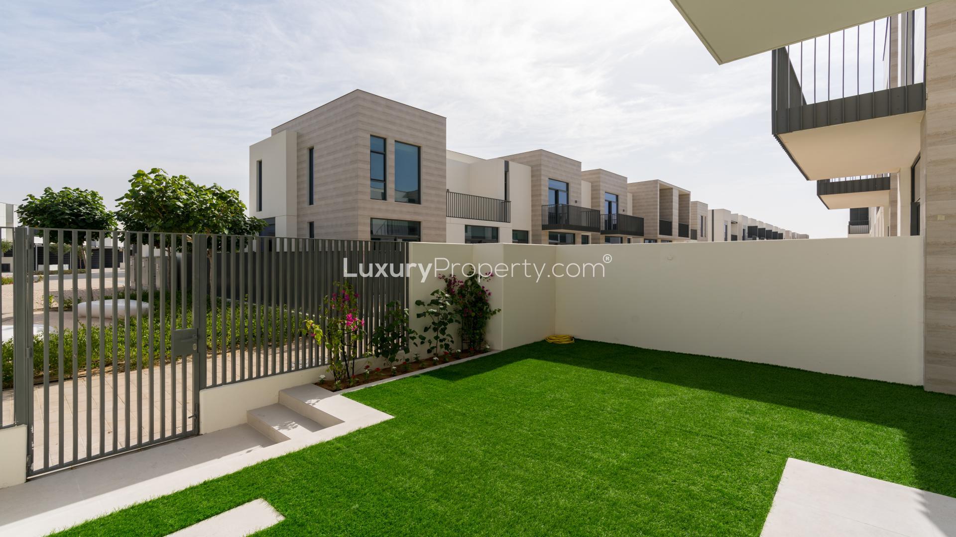 Bright living room in 3-bedroom villa, Arabian Ranches III, with garden view through glass doors