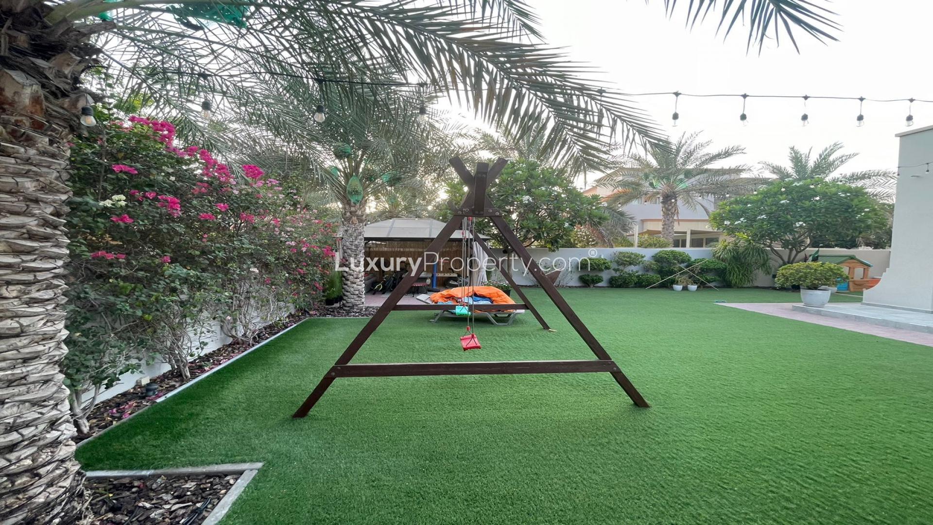 Outdoor garden with swing set and lush greenery in The Springs villa, Emirates Living