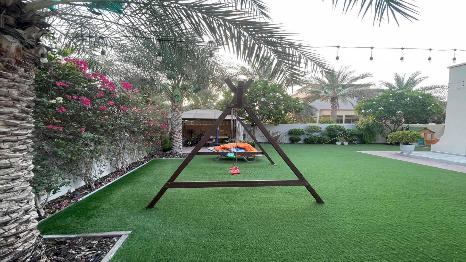Outdoor garden with swing set and lush greenery in The Springs villa, Emirates Living