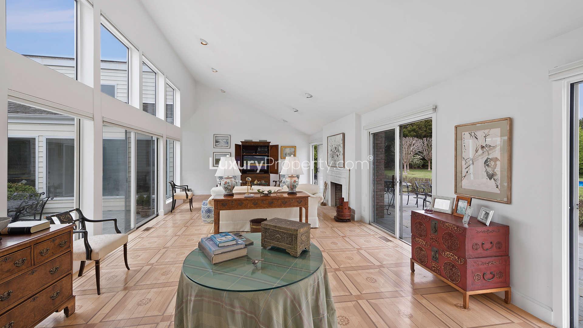 Luxurious living room with fireplace in Southampton villa, featuring elegant decor and large windows