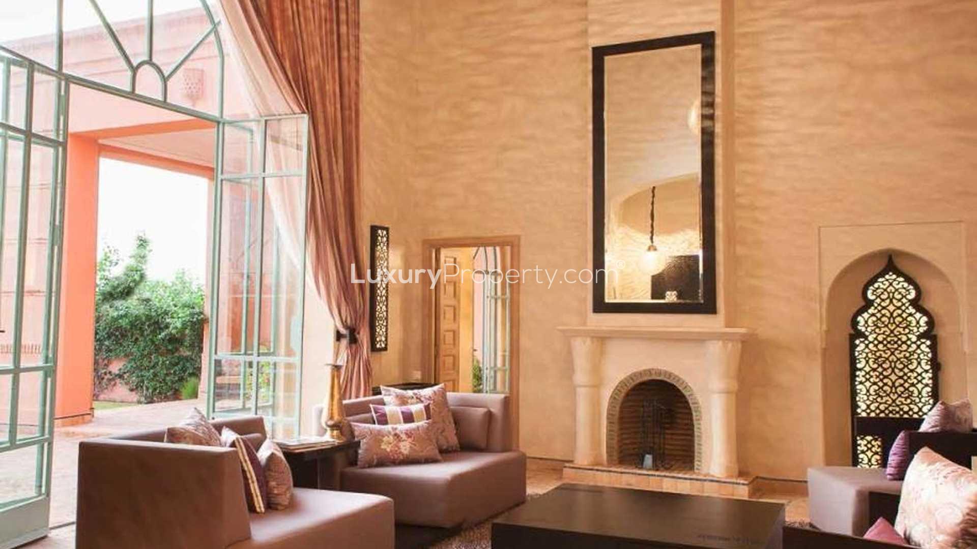 "Elegant brick columns and lush greenery at luxury villa in Amelkis Resorts, Marrakech.",Luxury villa living room with fireplace, elegant decor, Amelkis Resorts, Marrakech