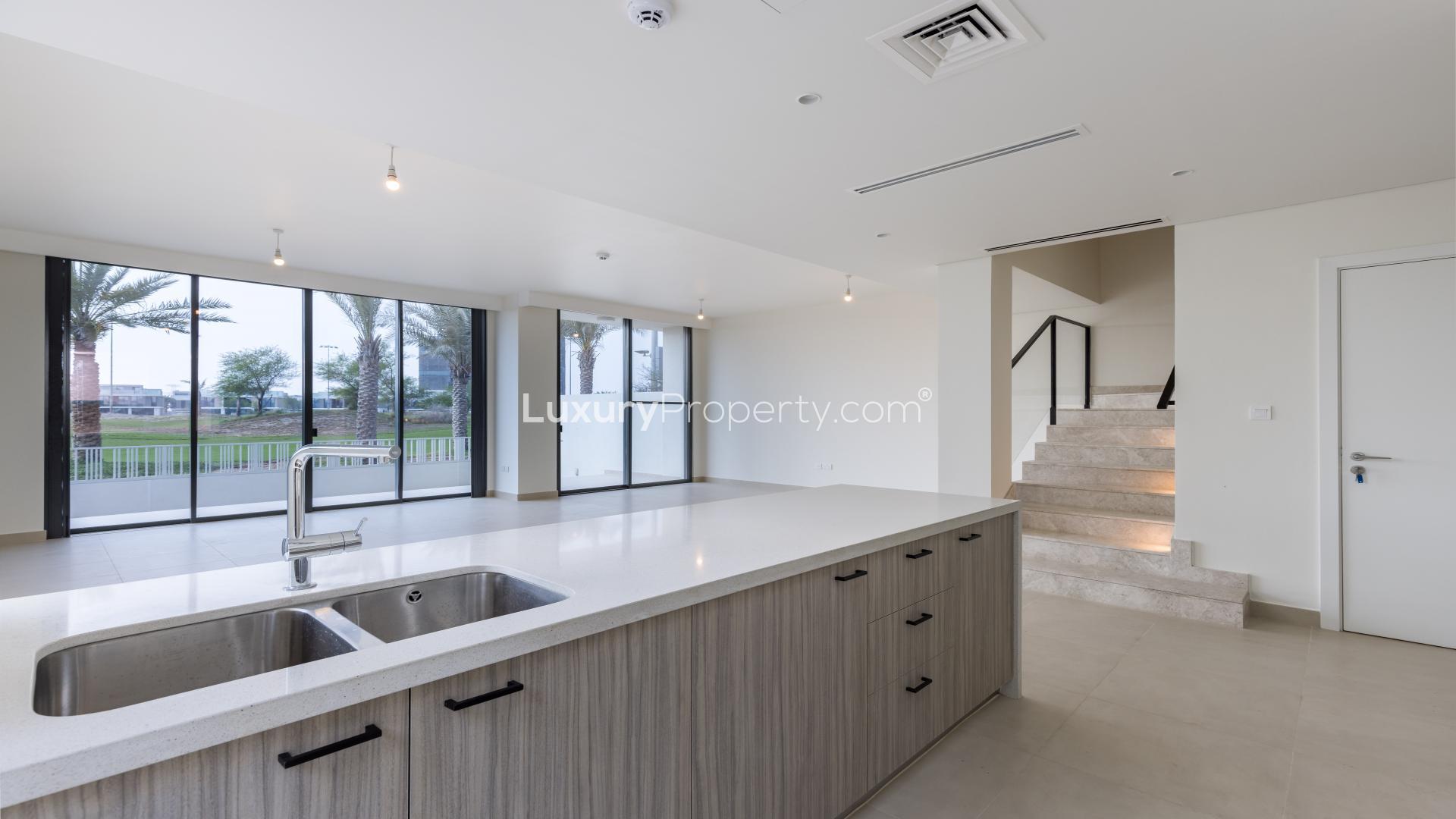 Open-plan living area in Dubai Hills Estate villa, featuring modern kitchen and staircase