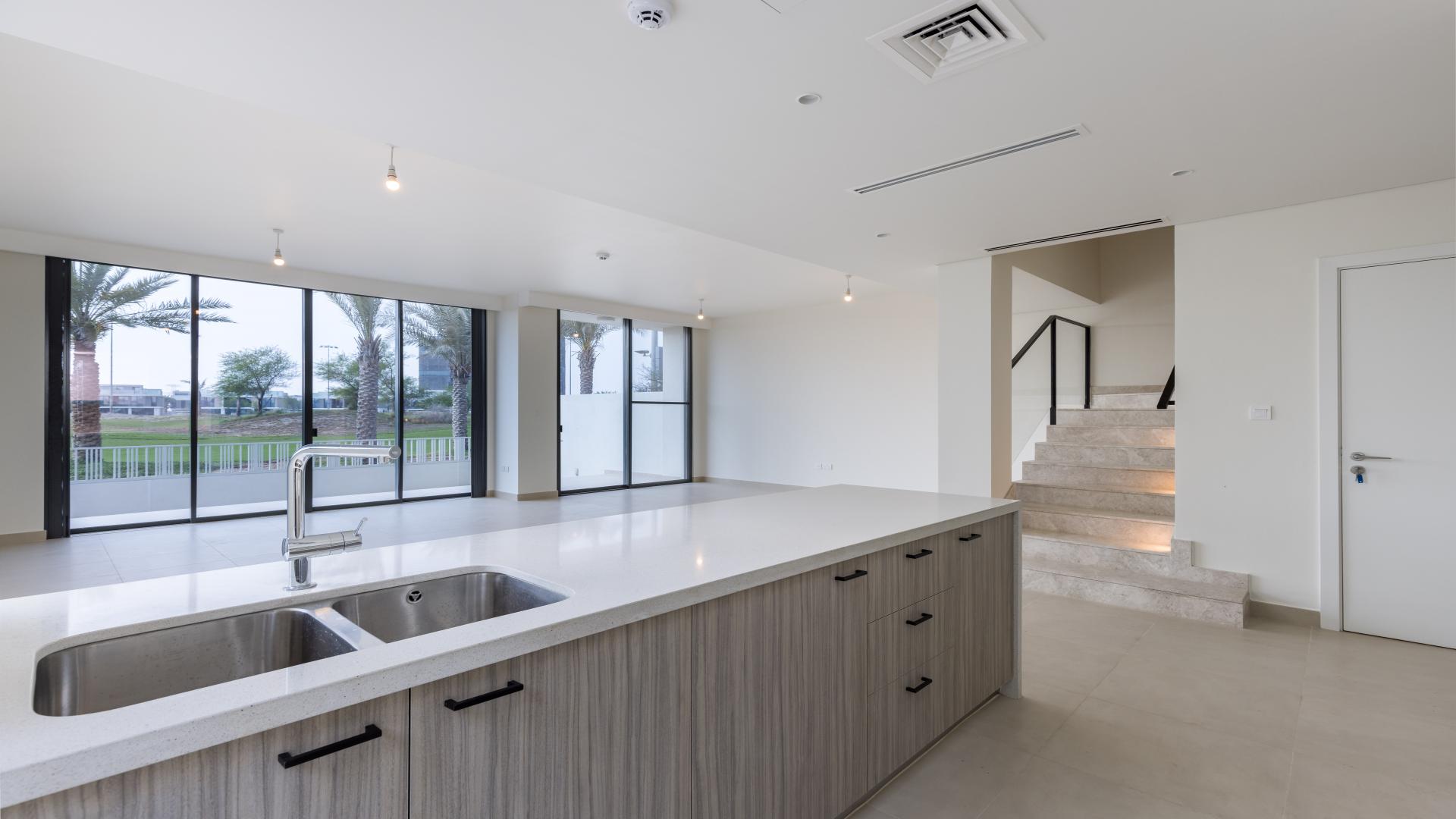 Open-plan living area in Dubai Hills Estate villa, featuring modern kitchen and staircase