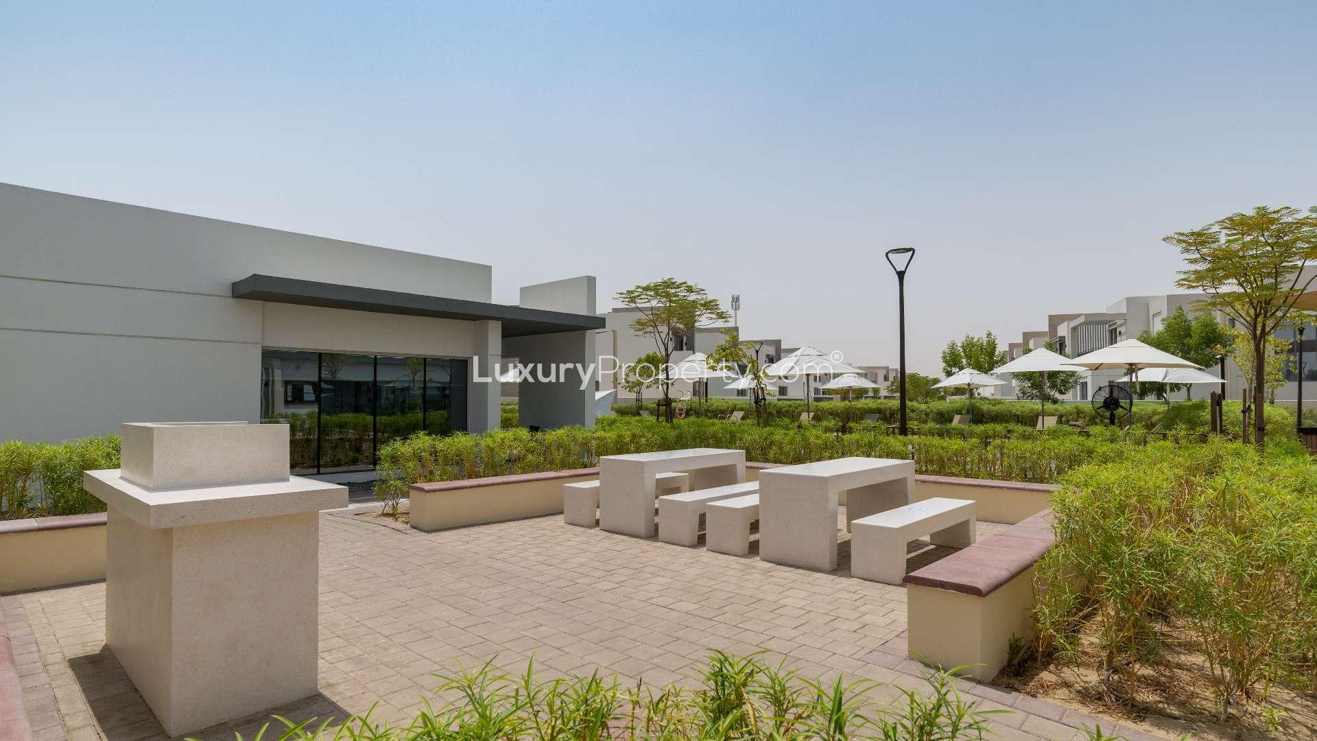 Outdoor pool area in Golf Links, Emaar South villa community, featuring loungers and umbrellas