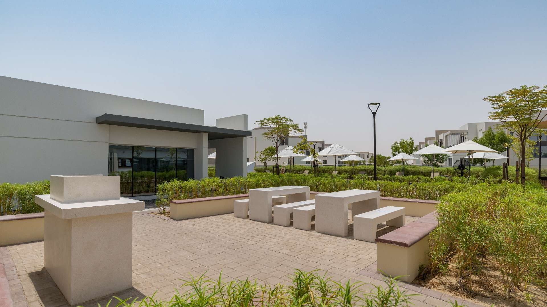 Outdoor pool area in Golf Links, Emaar South villa community, featuring loungers and umbrellas
