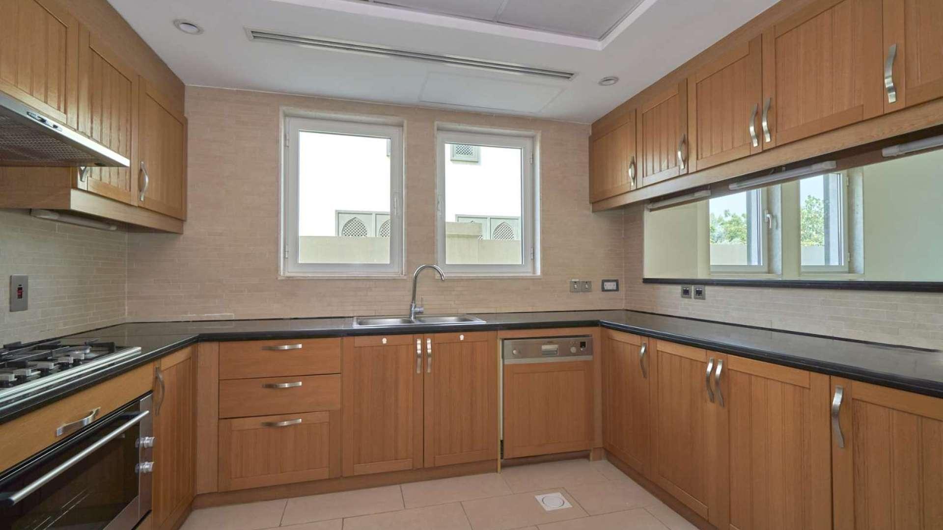 Open-plan kitchen and living area in Jumeirah Park villa, tiled floors and wooden cabinets