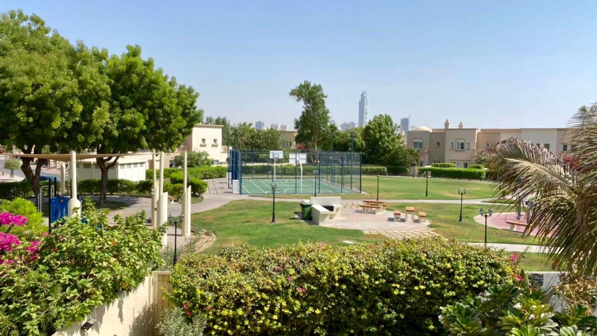 Sunny backyard patio with lush greenery in Springs 11 villa for sale