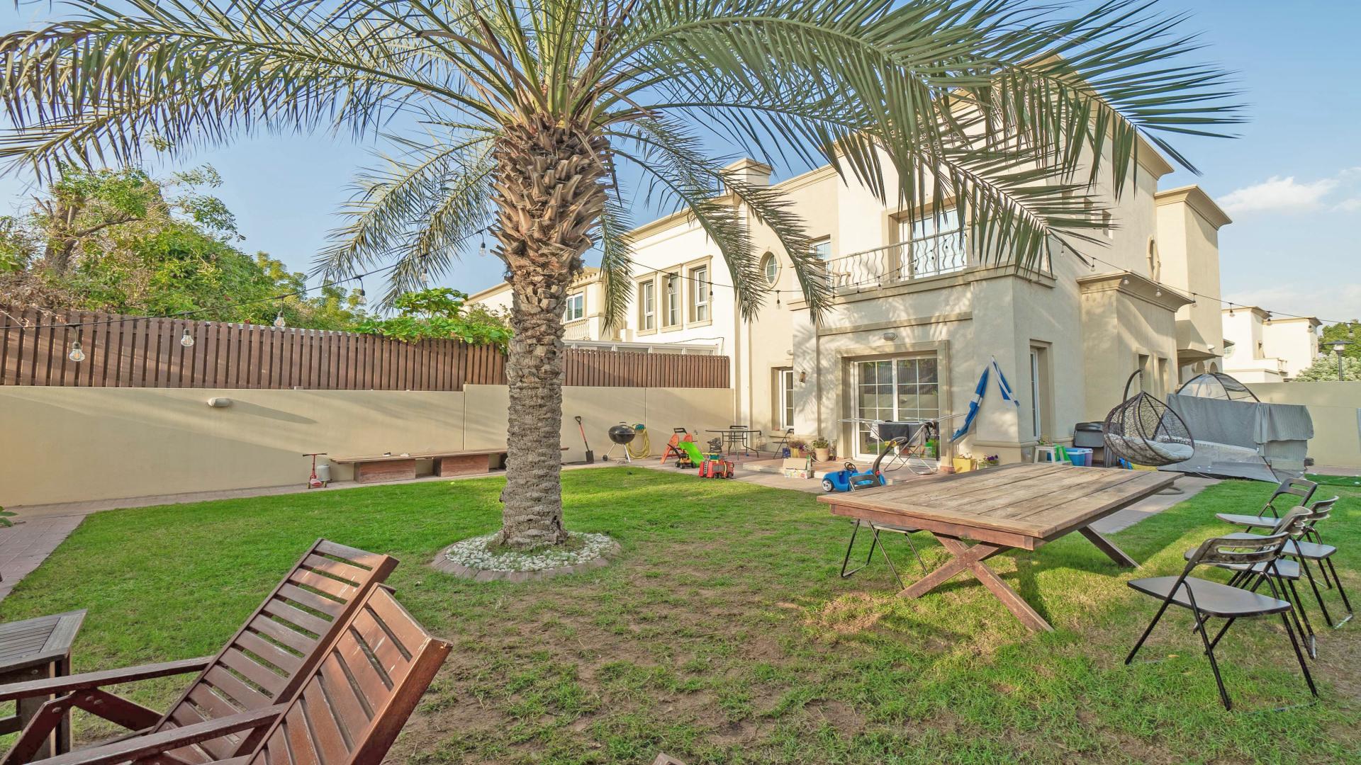Spacious backyard of 3-bedroom villa in The Springs, featuring lush garden and seating area