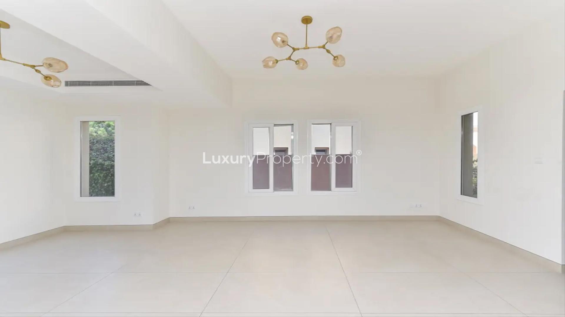 Empty living room in upgraded 3-bedroom villa, Springs 2, with modern chandelier and windows