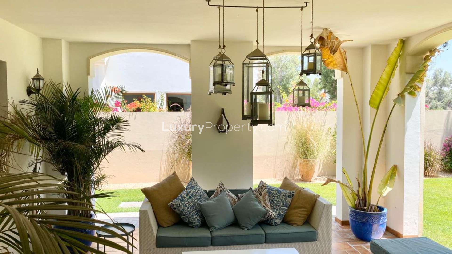 Outdoor seating area in Jumeirah Golf Estates villa with lush garden views