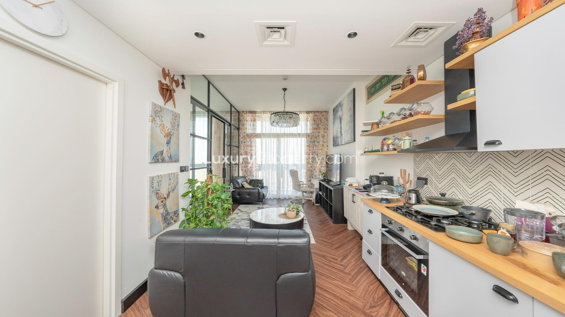 Apartment living area with modern decor, open kitchen, and sliding bedroom door in Dubai Hills
