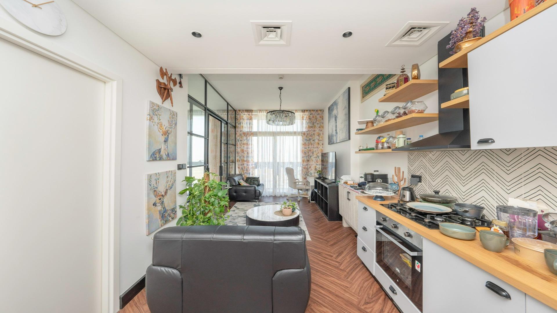 Apartment living area with modern decor, open kitchen, and sliding bedroom door in Dubai Hills