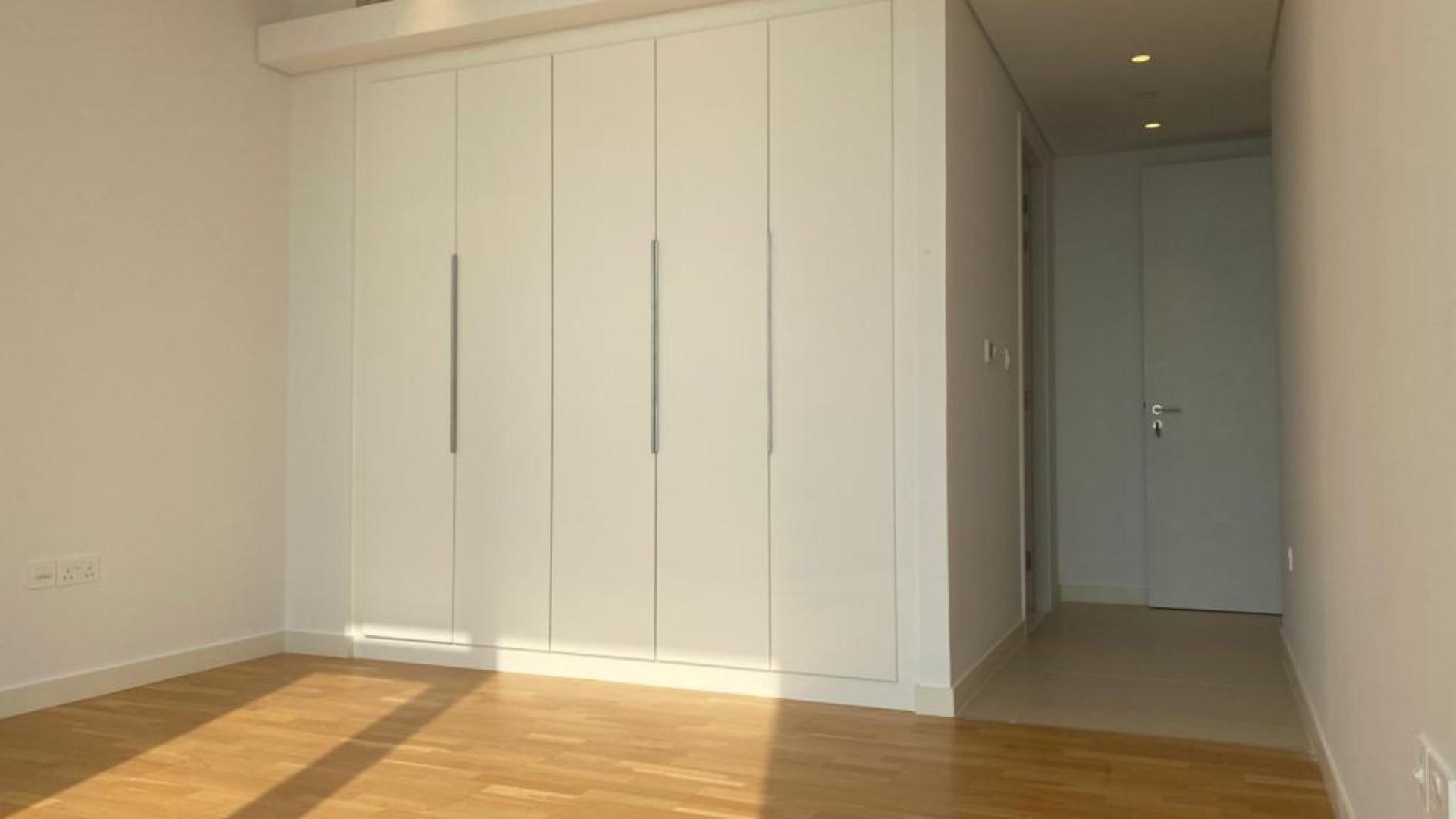 "Spacious bedroom with built-in wardrobes in Bluewaters Residences apartment, available for sale.",Empty room with wooden floor and large window overlooking ocean view at Bluewaters Residences