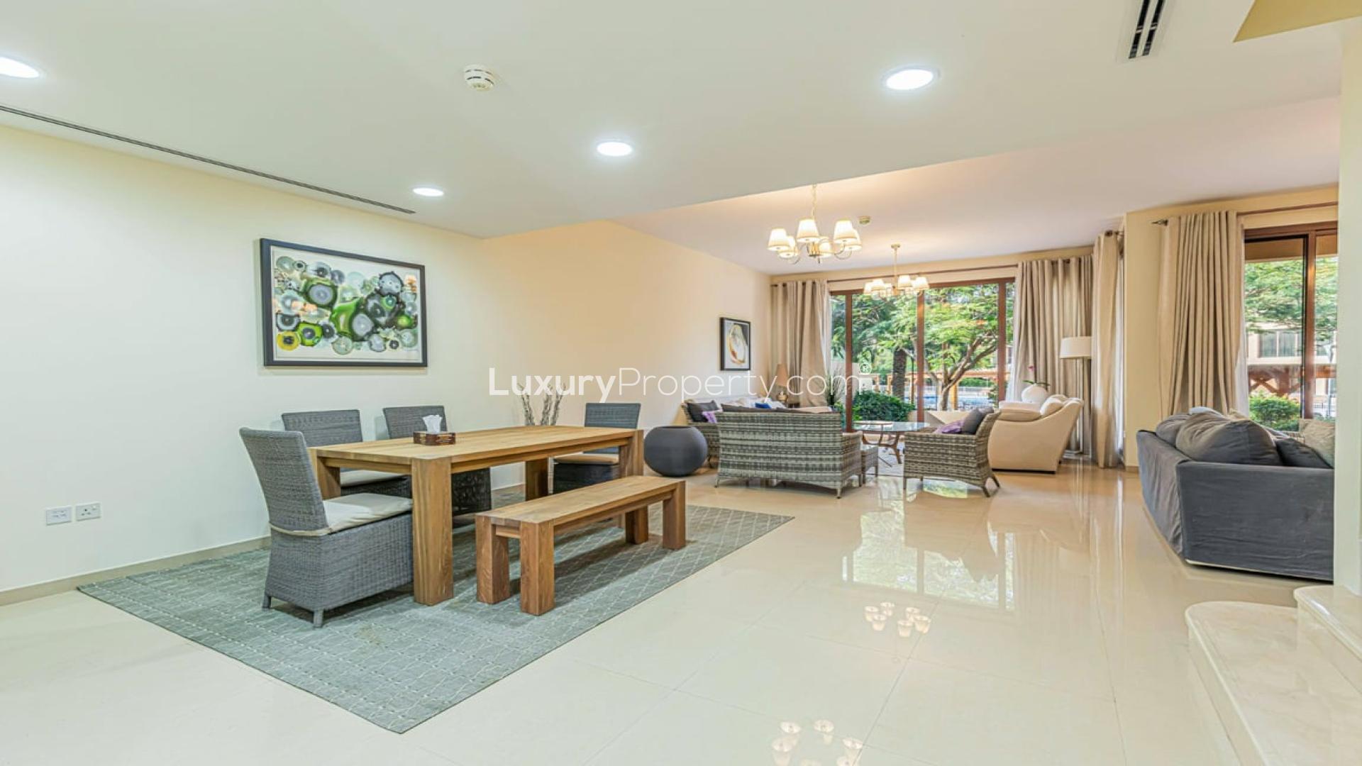 Modern kitchen in 4-bedroom townhouse, Jumeirah Islands, with wooden cabinets and dining area