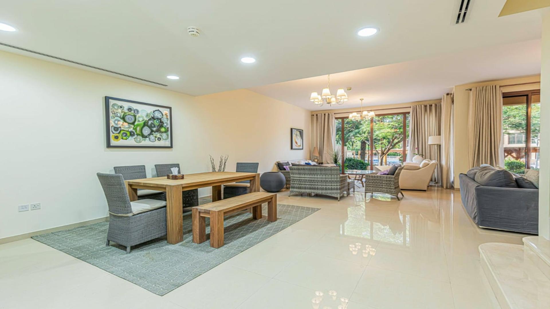 Modern kitchen in 4-bedroom townhouse, Jumeirah Islands, with wooden cabinets and dining area