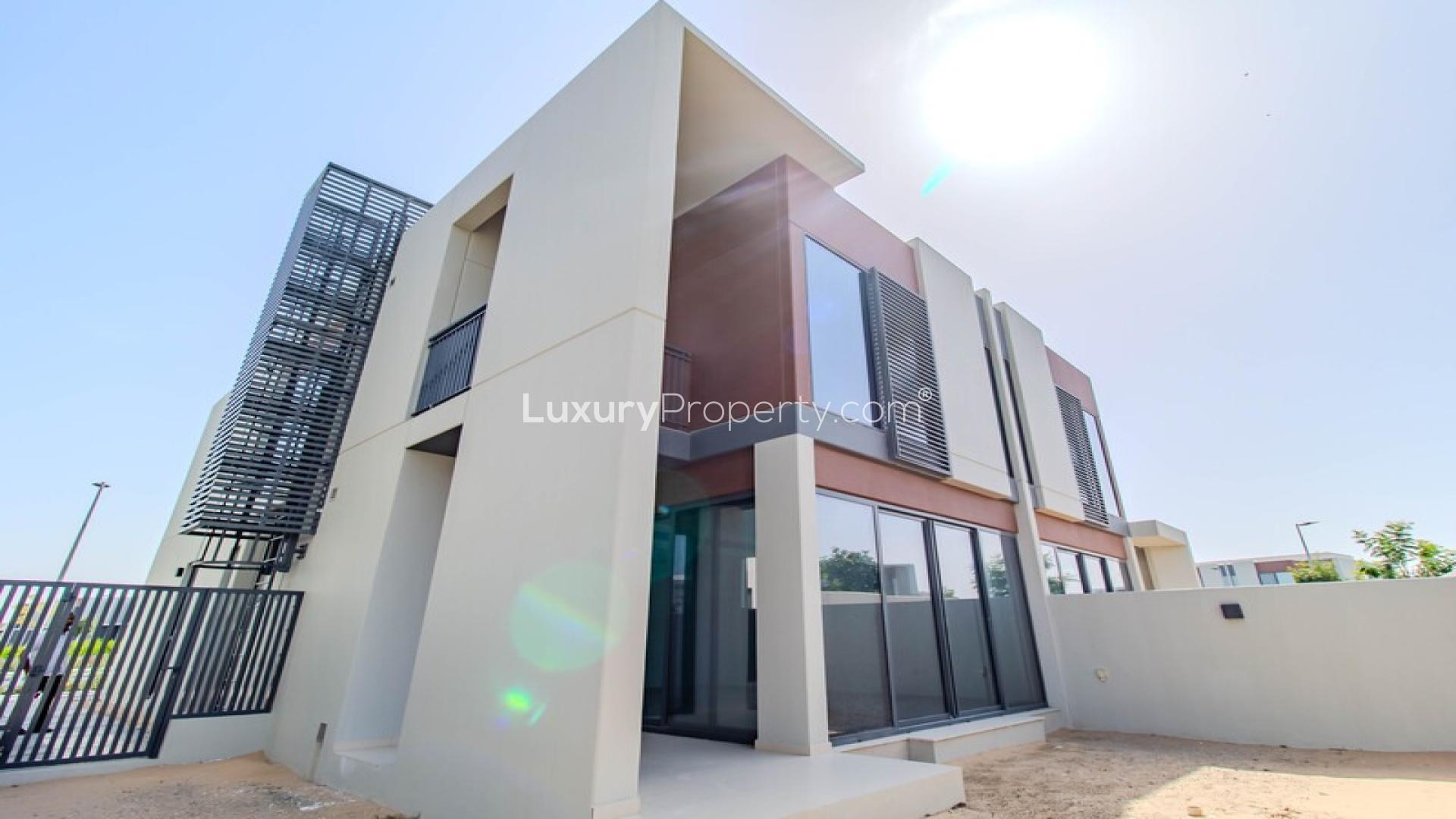 Outdoor pool area at Cherrywoods Dubailand townhouse community, featuring lounge chairs and umbrellas