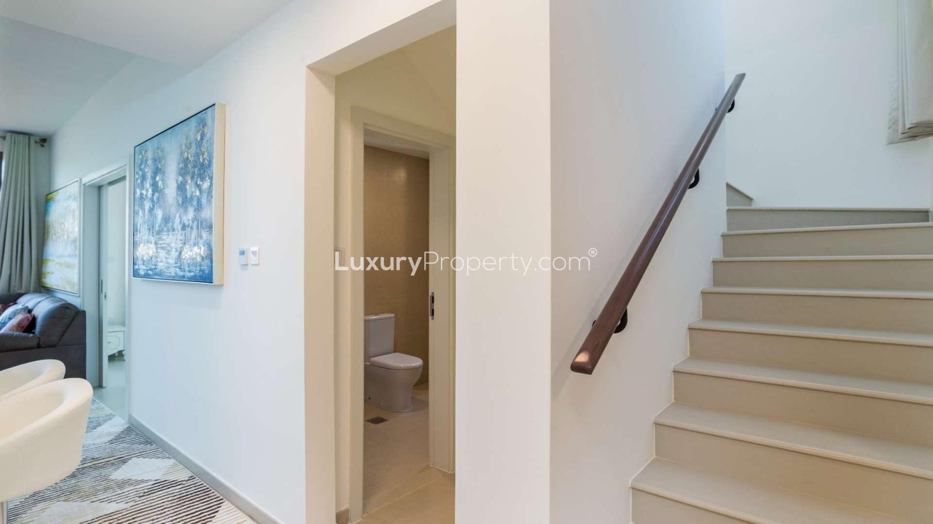 "Modern 4-bedroom corner townhouse in Naseem Town Square with landscaped garden and street view.",Hallway with staircase and bathroom in 4-bedroom townhouse, Naseem Town Square