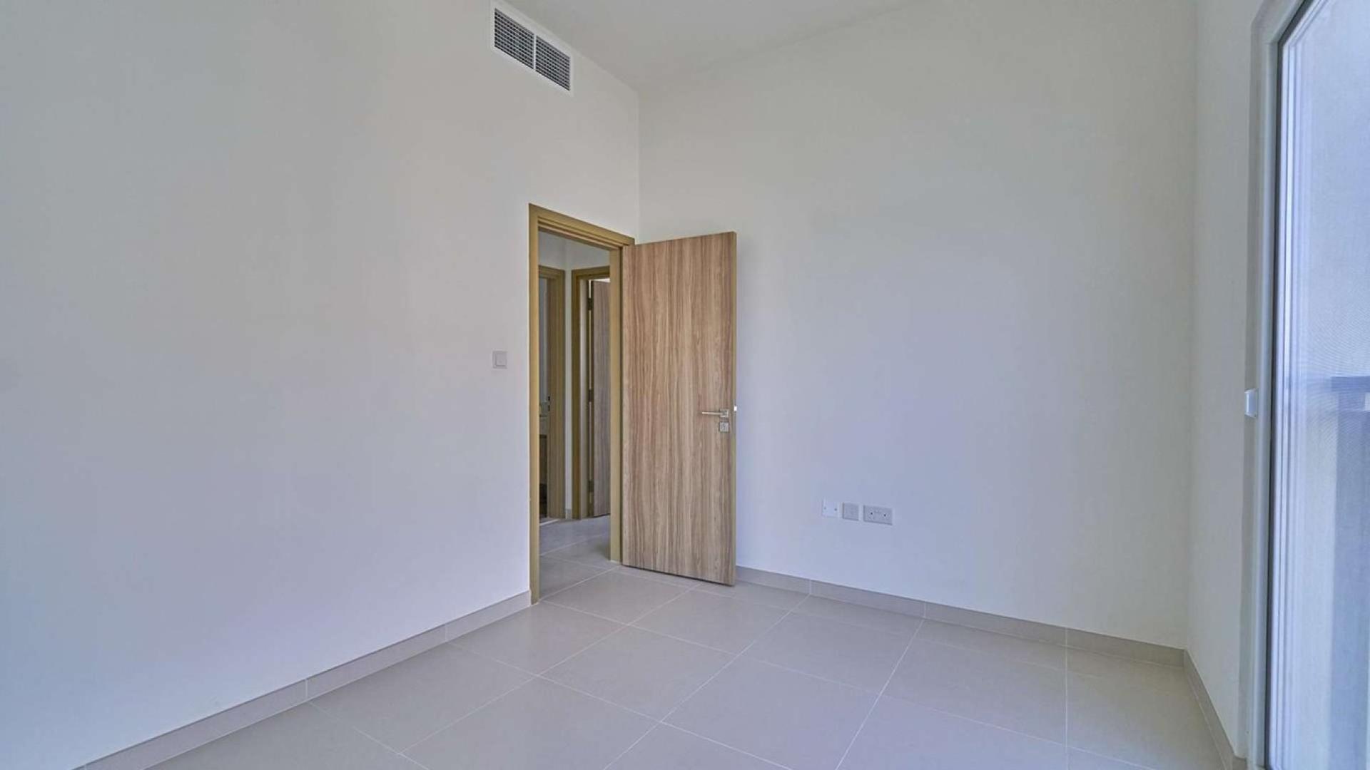 Alt text: "Vastu-compliant townhouse near pool in Villanova, Dubai Land, for sale, 4 bedrooms.",Empty room in Vastu-compliant townhouse, Dubai Land Villanova, featuring wooden door and window