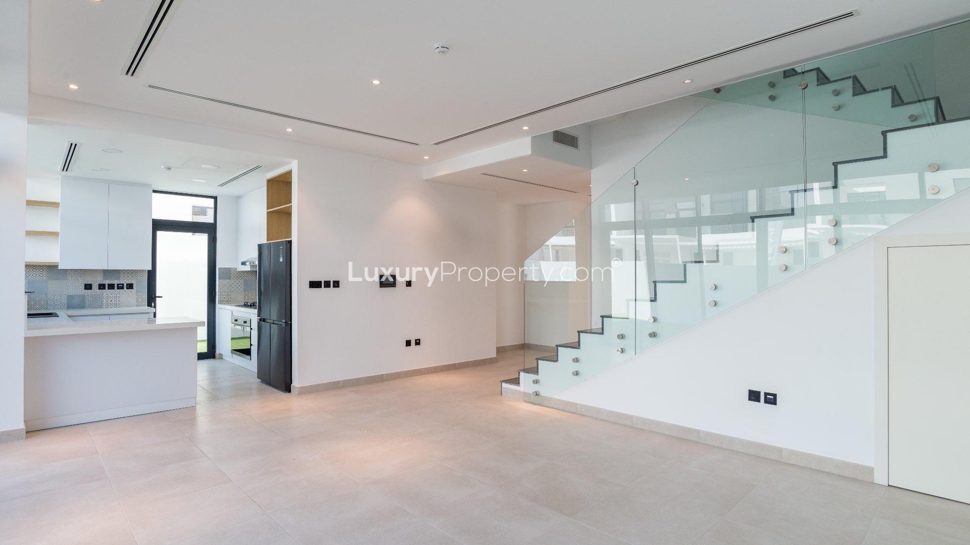 "Modern townhouse exterior with spacious garden in Jumeirah Luxury, Jumeirah Golf Estates.",Modern kitchen and staircase in Jumeirah Luxury townhouse, Flower Villa for sale