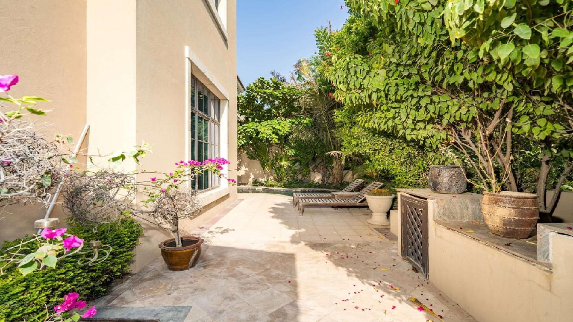 Sunny patio with lush greenery at Jumeirah Golf Estates villa, Earth community