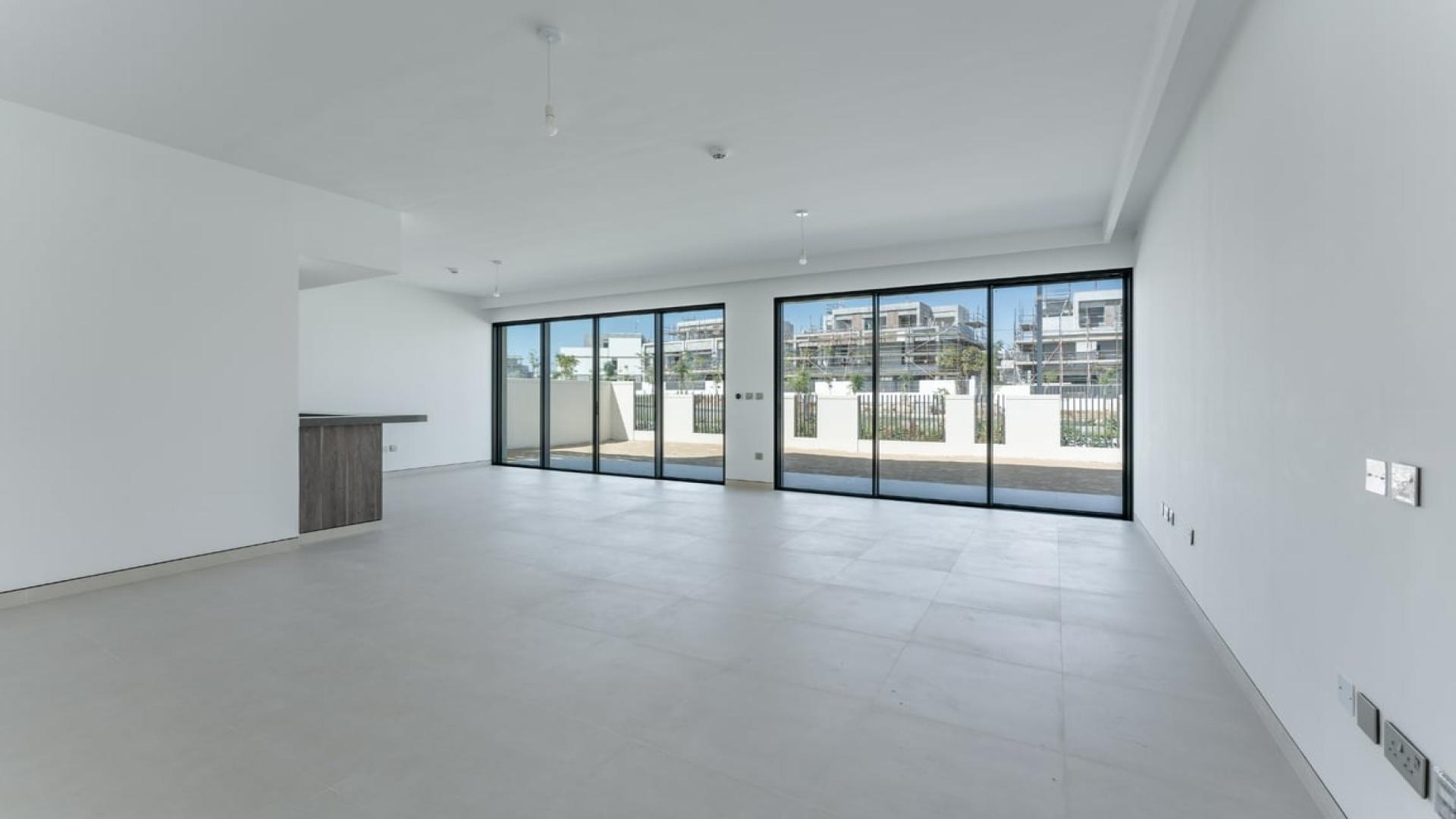 Modern open-plan living area in Tilal Al Ghaf Harmony villa with large windows and patio