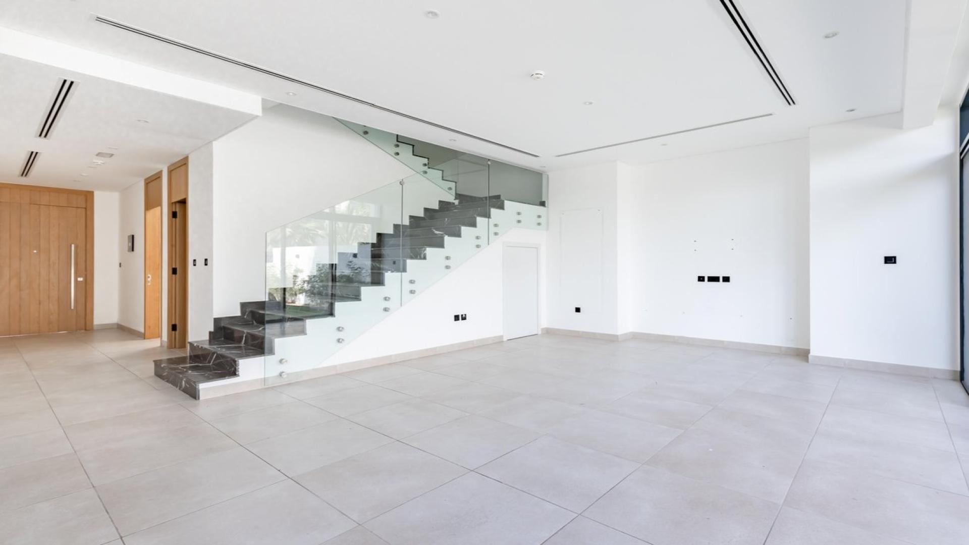 Modern villa interior with large glass doors overlooking garden in Jumeirah Luxury, Jumeirah Golf Estates