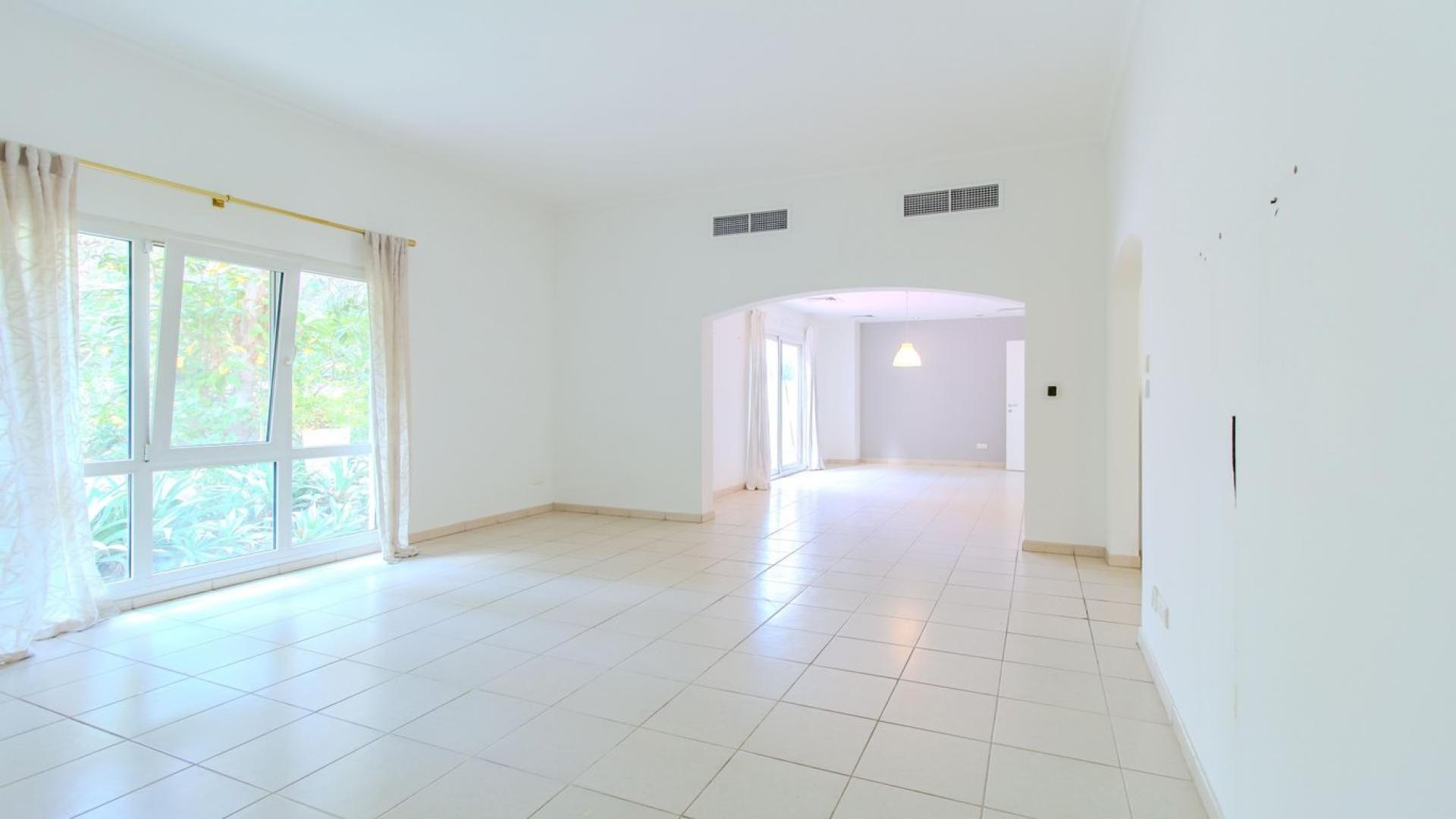 Empty living room with large window, tiled floor, and garden view in Meadows 9 villa