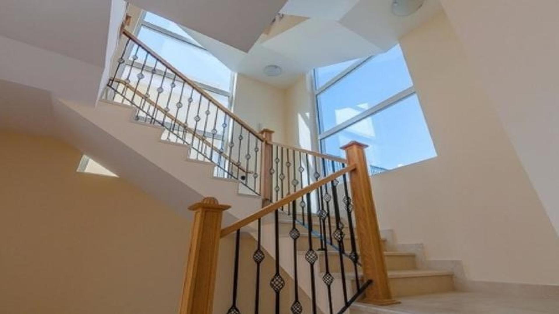 "Elegant staircase with iron railing in Jumeirah Park Legacy Villa, Dubai for rent.",Modern kitchen in single-row Legacy Villa, Jumeirah Park, featuring wooden cabinetry and large windows