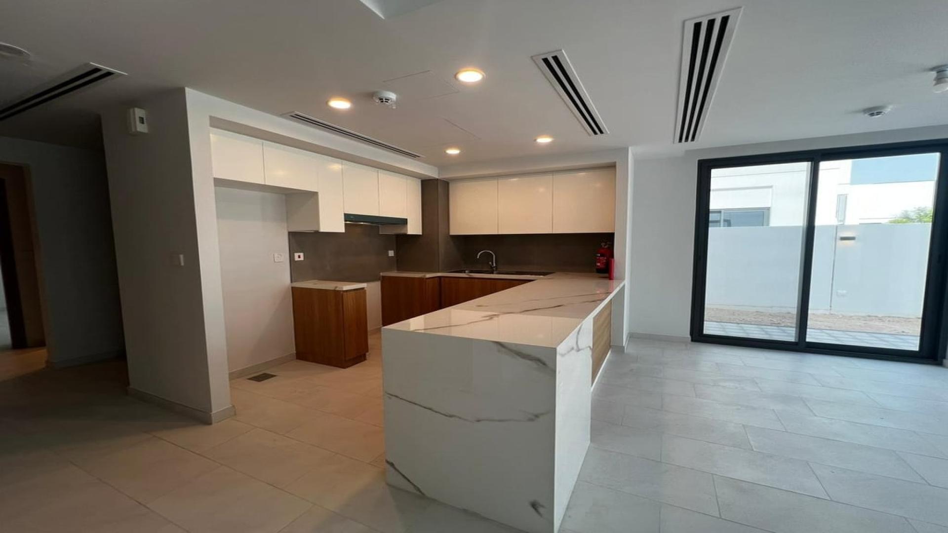 Modern open-plan kitchen and living area in Villanova villa, Dubai Land, available for rent