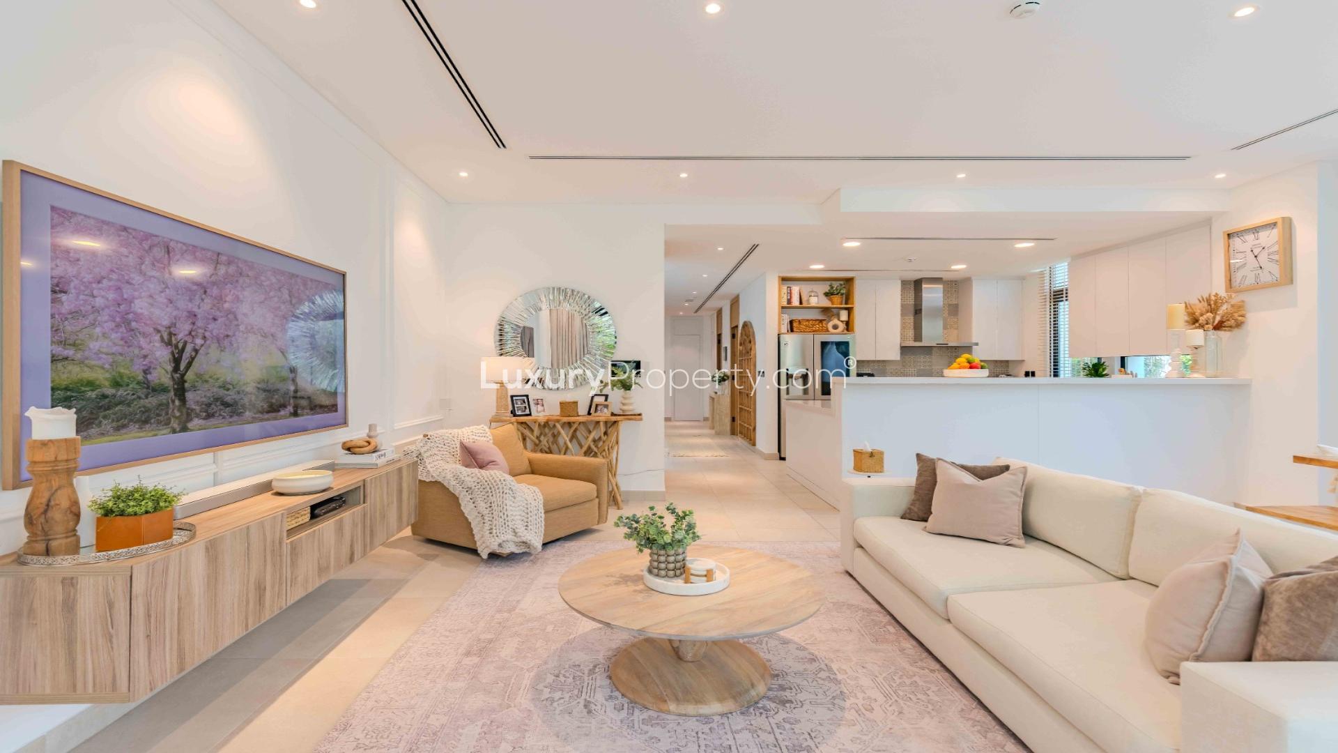 Modern living room in upgraded Jumeirah Golf Estates villa, featuring open kitchen and garden view