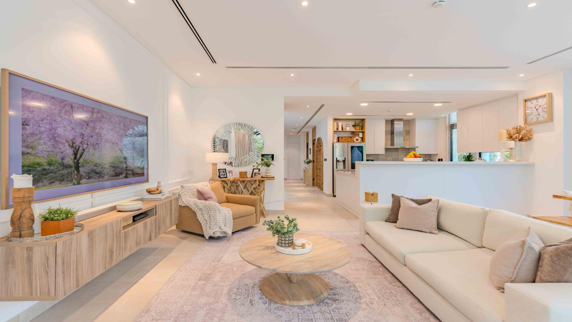 Modern living room in upgraded Jumeirah Golf Estates villa, featuring open kitchen and garden view