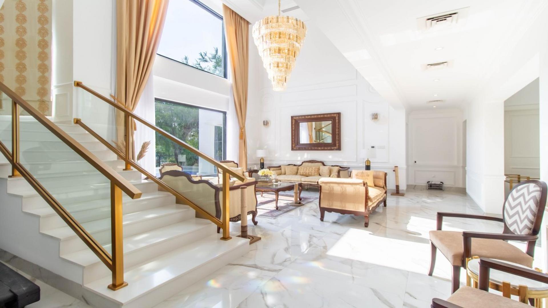 Luxurious sunlit interior of Jumeirah Islands villa with elegant staircase and chandelier