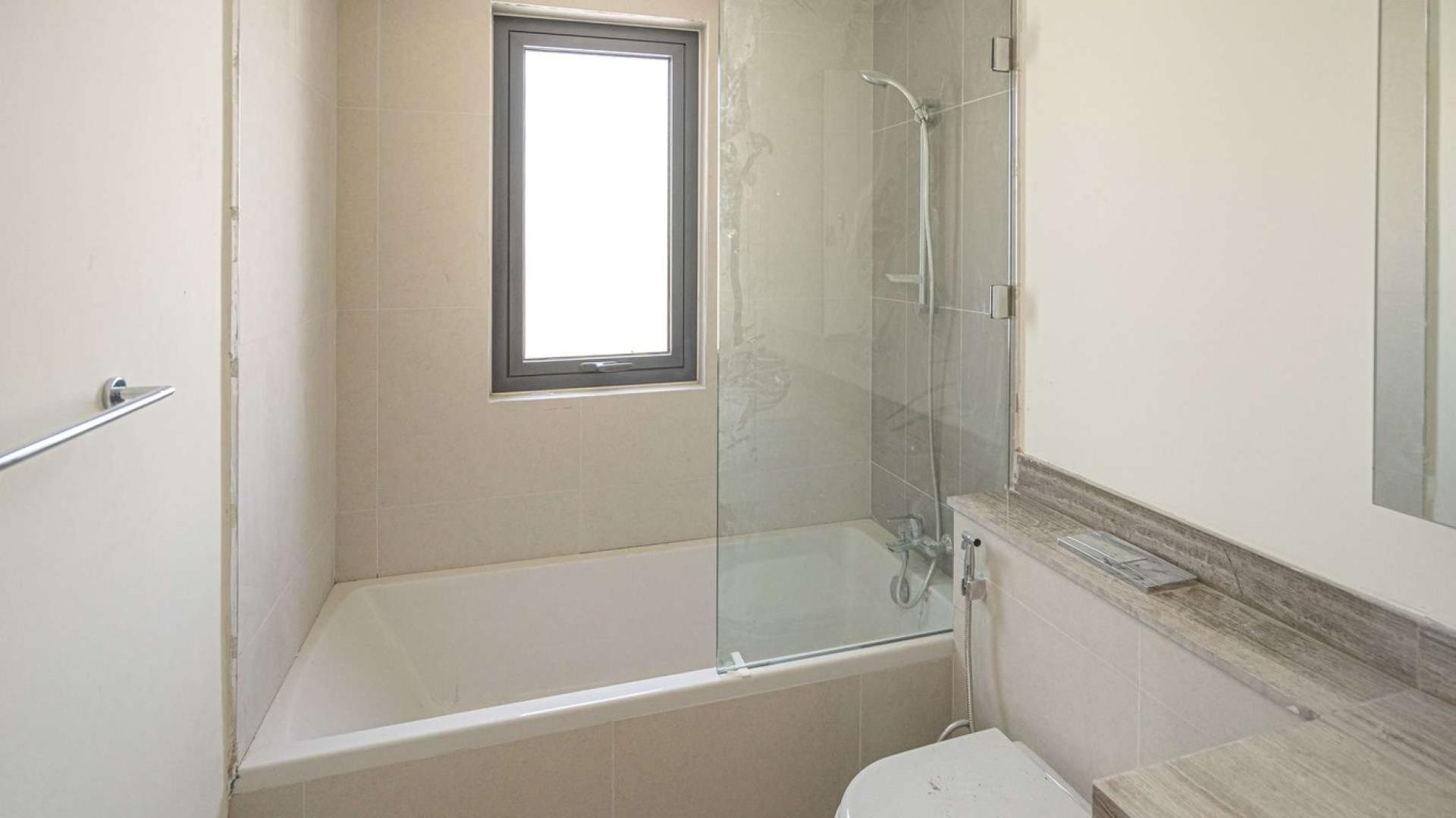 "Bright living room with large windows in Dubai Hills Estate villa, Maple community.",Modern bathroom with bathtub and window in Dubai Hills Estate villa, Maple sub-community