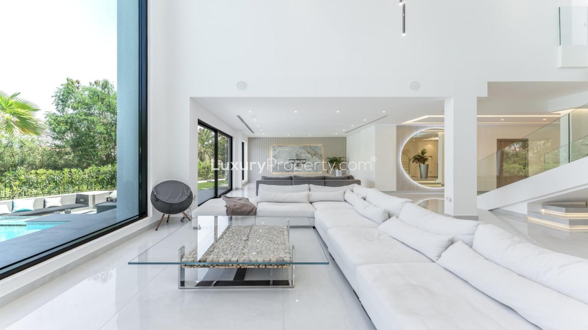 Luxurious villa living room with modern finishes, large windows, and pool view in Jumeirah Islands