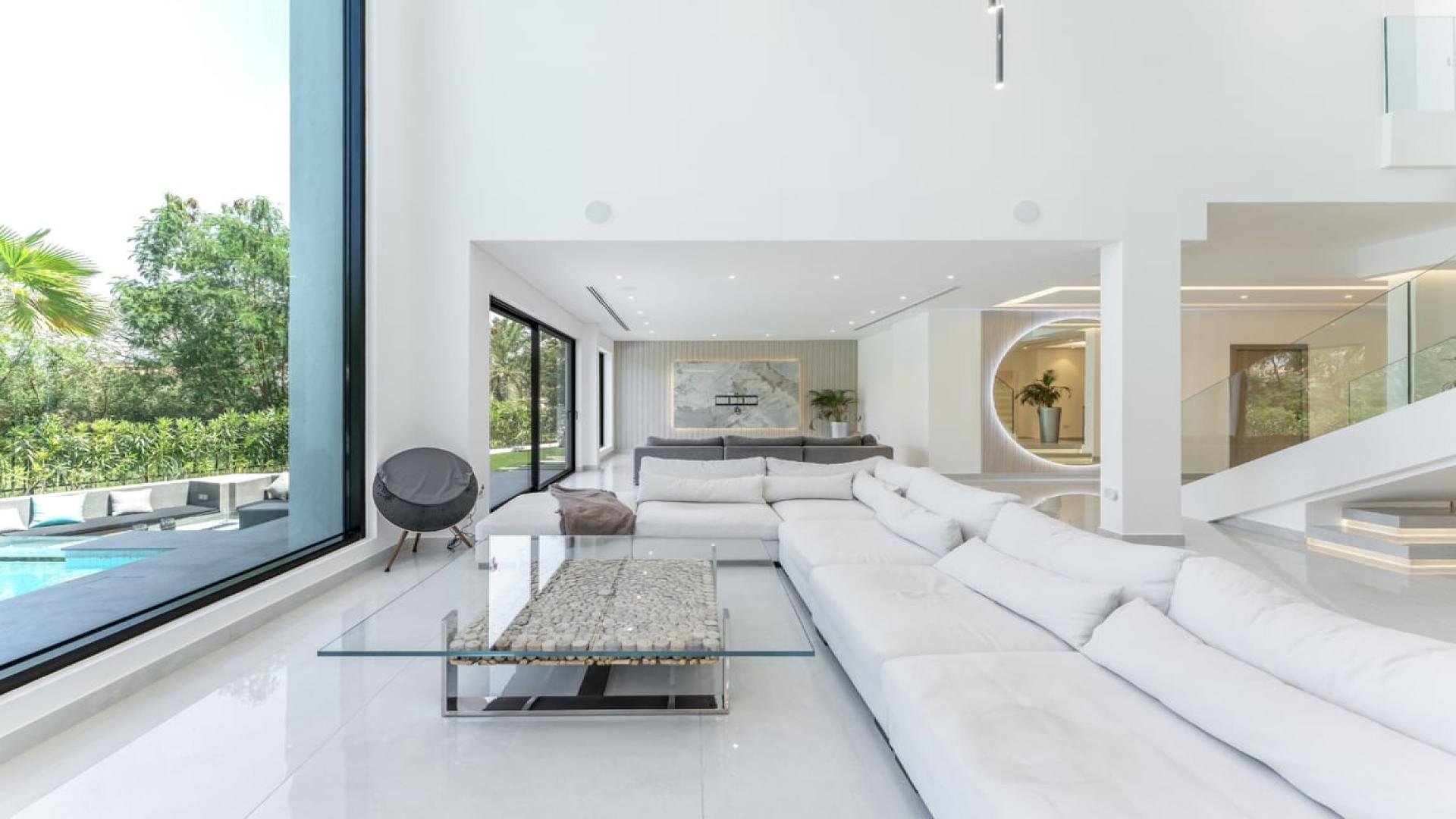 Luxurious villa living room with modern finishes, large windows, and pool view in Jumeirah Islands