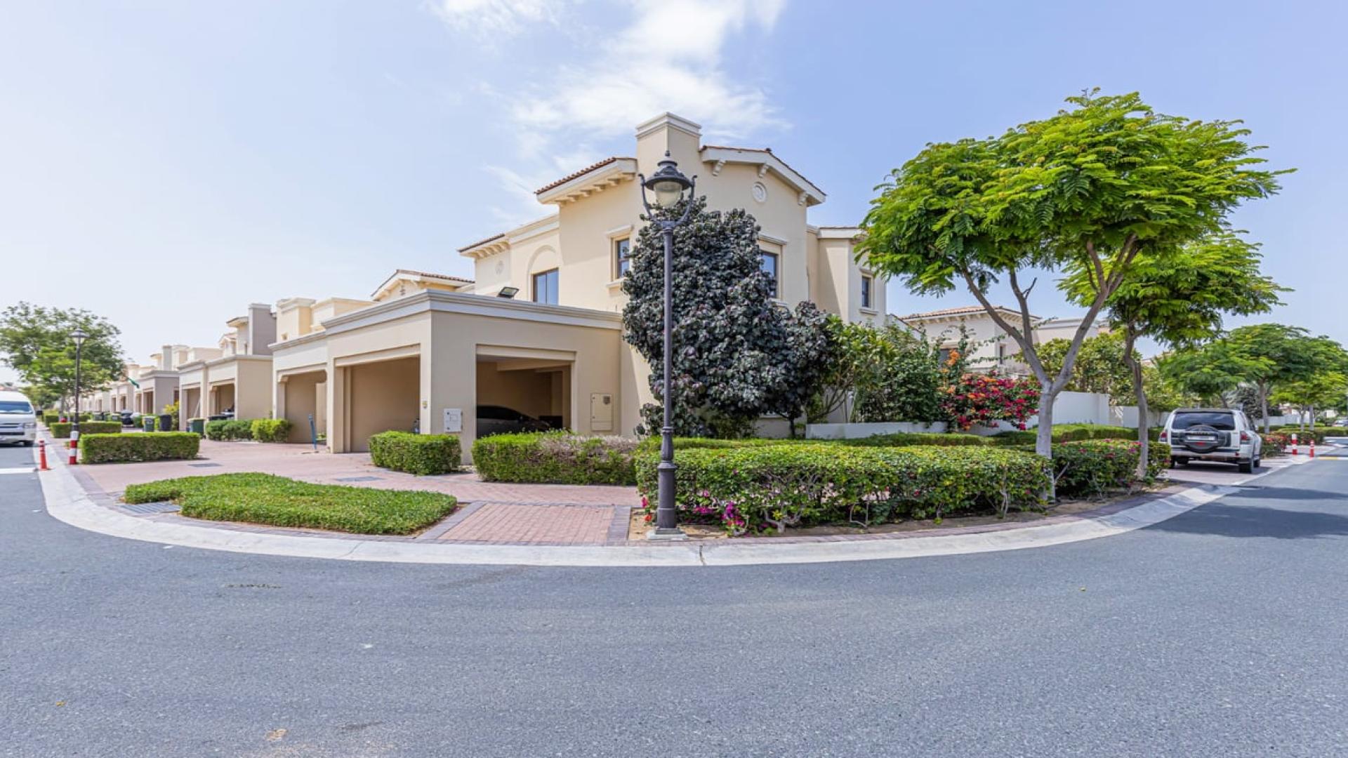 Corner unit villa living room with gray sofas, open layout, and kitchen view in Mira