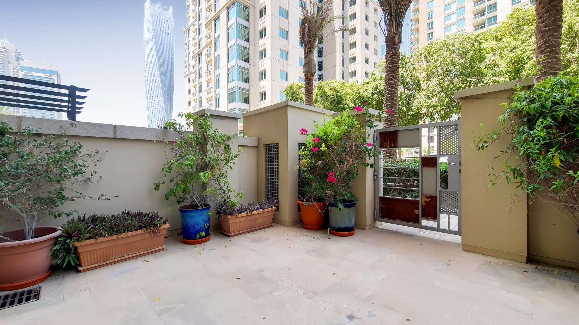 Ground-floor apartment interior with large windows, private terrace view, Dubai Marina