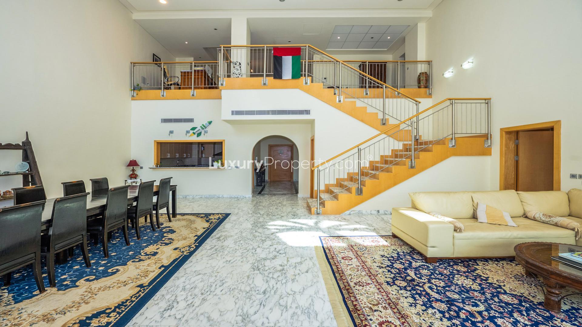 "Spacious balcony view from Shoreline Apartments penthouse, Palm Jumeirah, with city skyline.",Luxurious living room in Palm Jumeirah duplex penthouse, marble floors, elegant staircase, spacious layout
