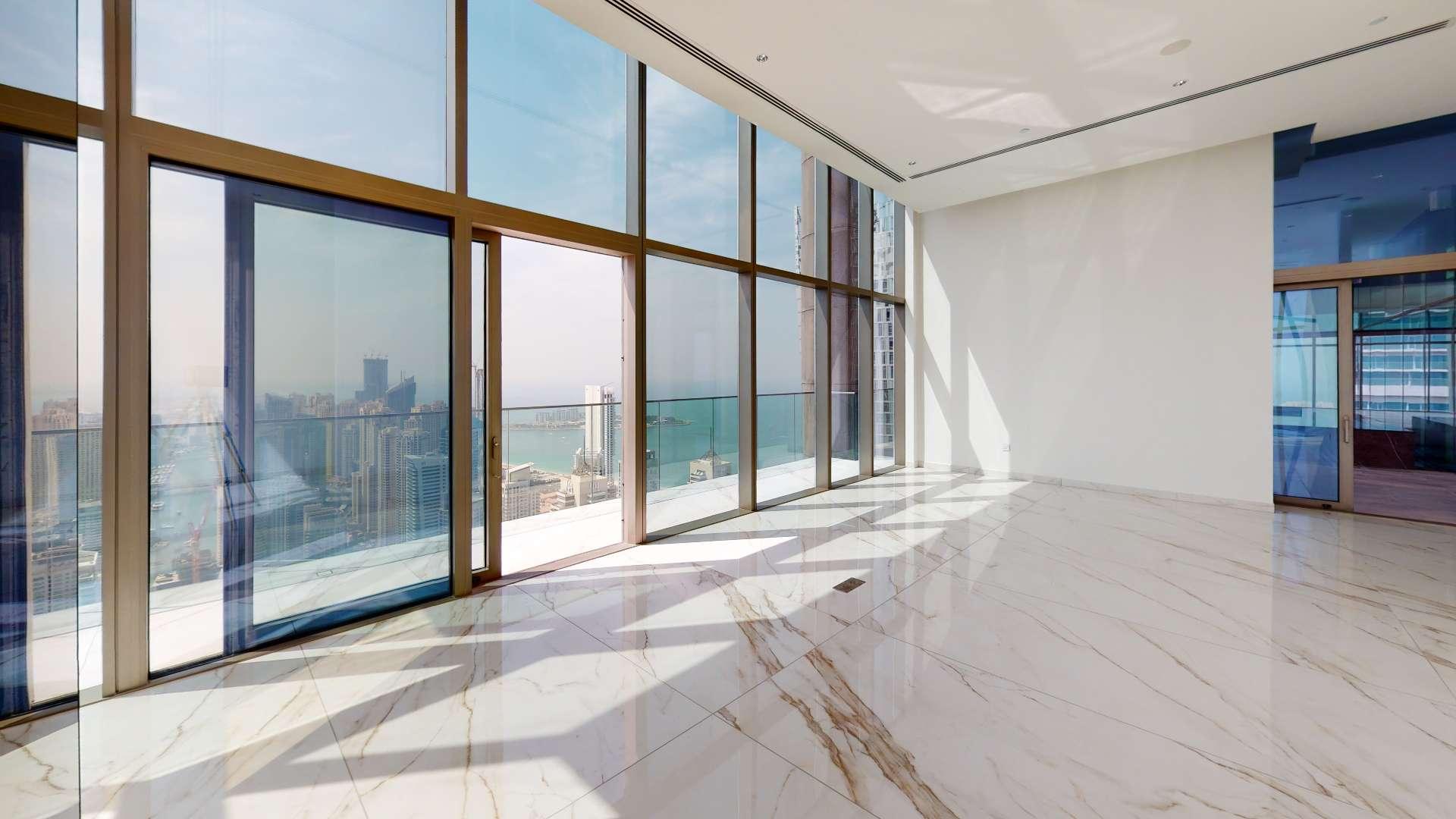 Spacious living area in Dubai Marina penthouse with floor-to-ceiling windows and city views