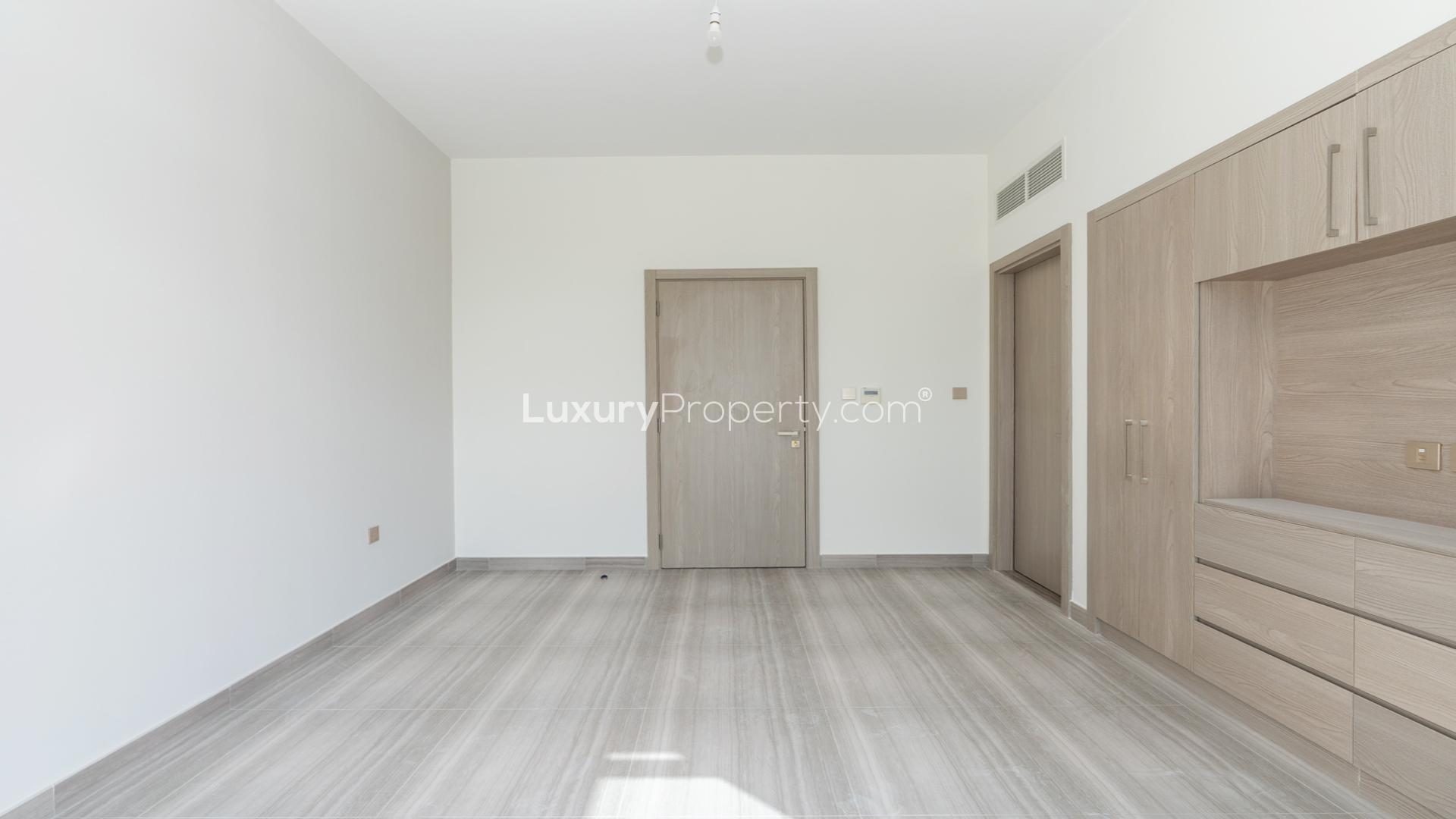 Backyard view of townhouse in Damac Hills Trinity, park access, green lawn, sunny day