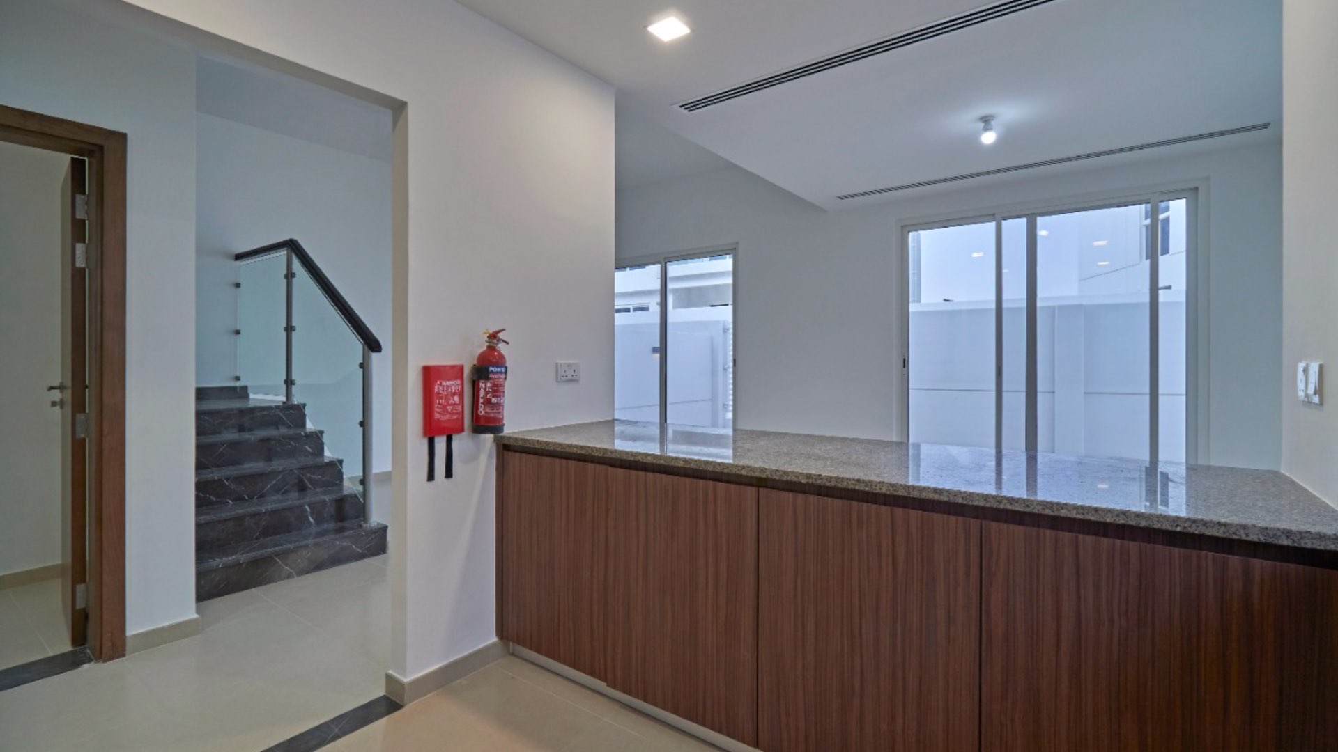 Modern kitchen in 4-bedroom villa, Arabella Townhouses, Mudon, featuring wood cabinets and mosaic backsplash