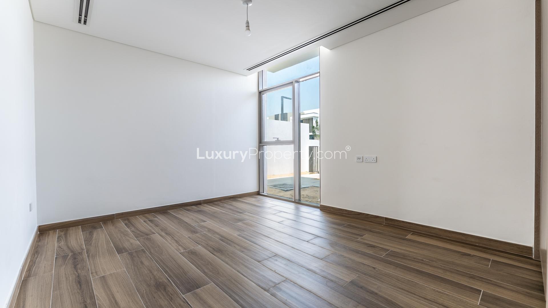 Empty bedroom with wooden floors, mirrored closet, and bathroom view in Al Furjan townhouse